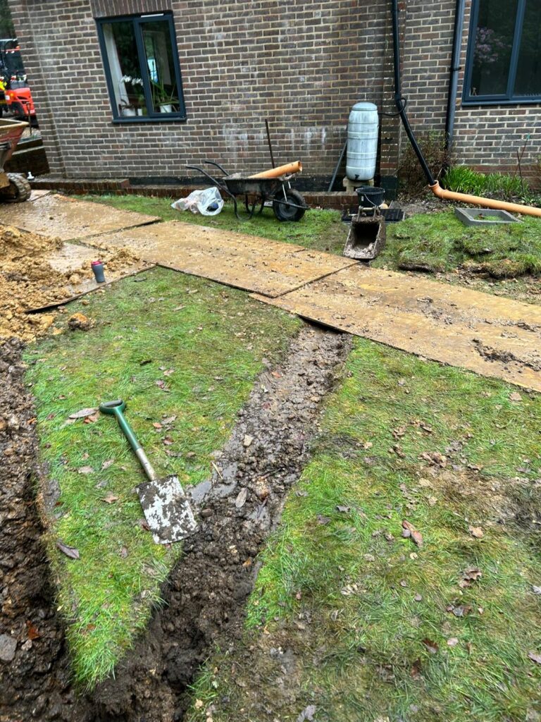 Excavation work exposing a damaged underground drain for emergency repair at a residential property.