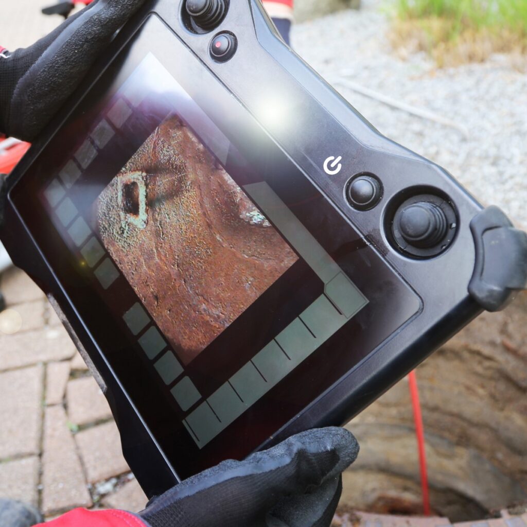 Drainage engineer reviewing CCTV drain survey footage to identify damage inside underground pipework.