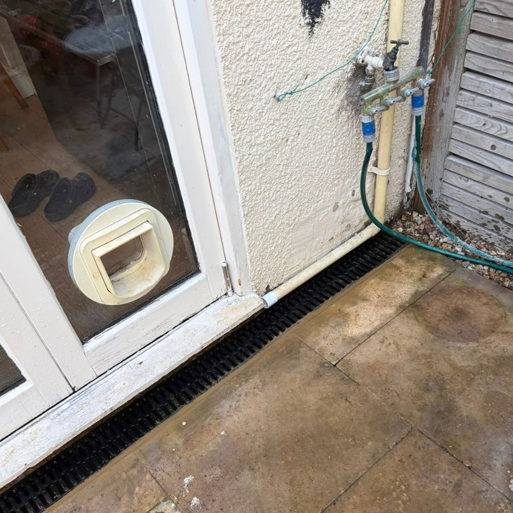 Grated channel drain beside a glazed doorway and paved patio