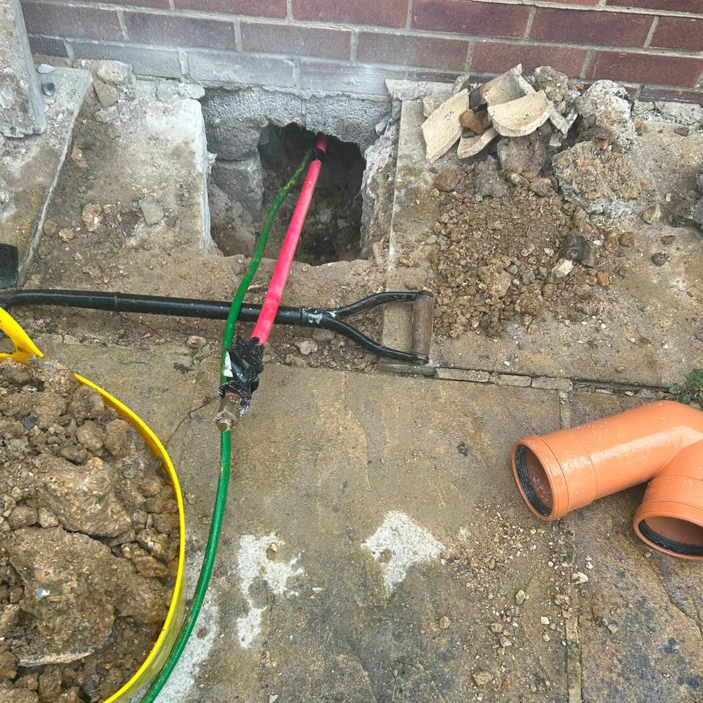 Underground drainage pipework exposed beside a property during repair work