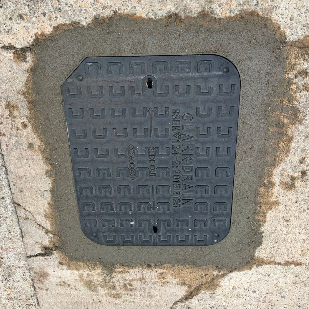 Open brick-lined inspection chamber with a curved drainage channel and grey surround
