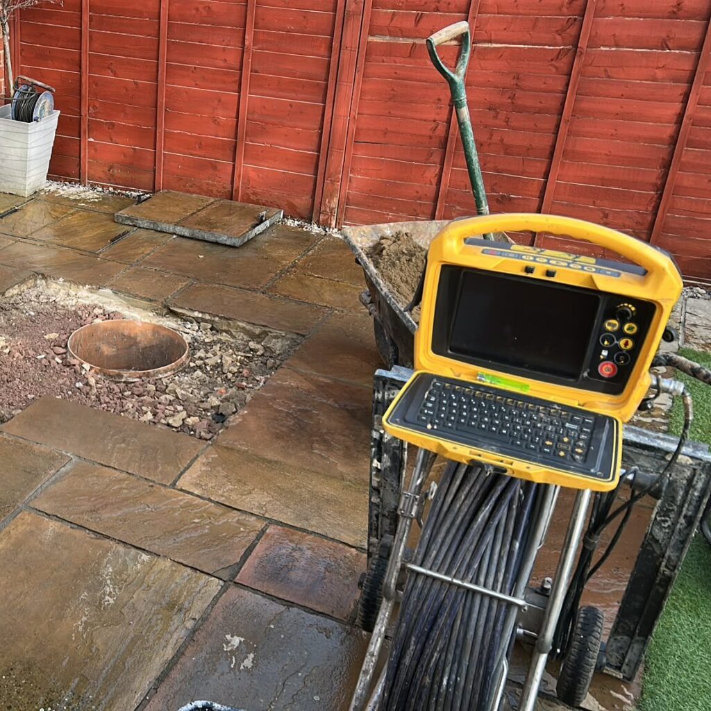 CCTV drain survey monitor and camera reel beside a patio