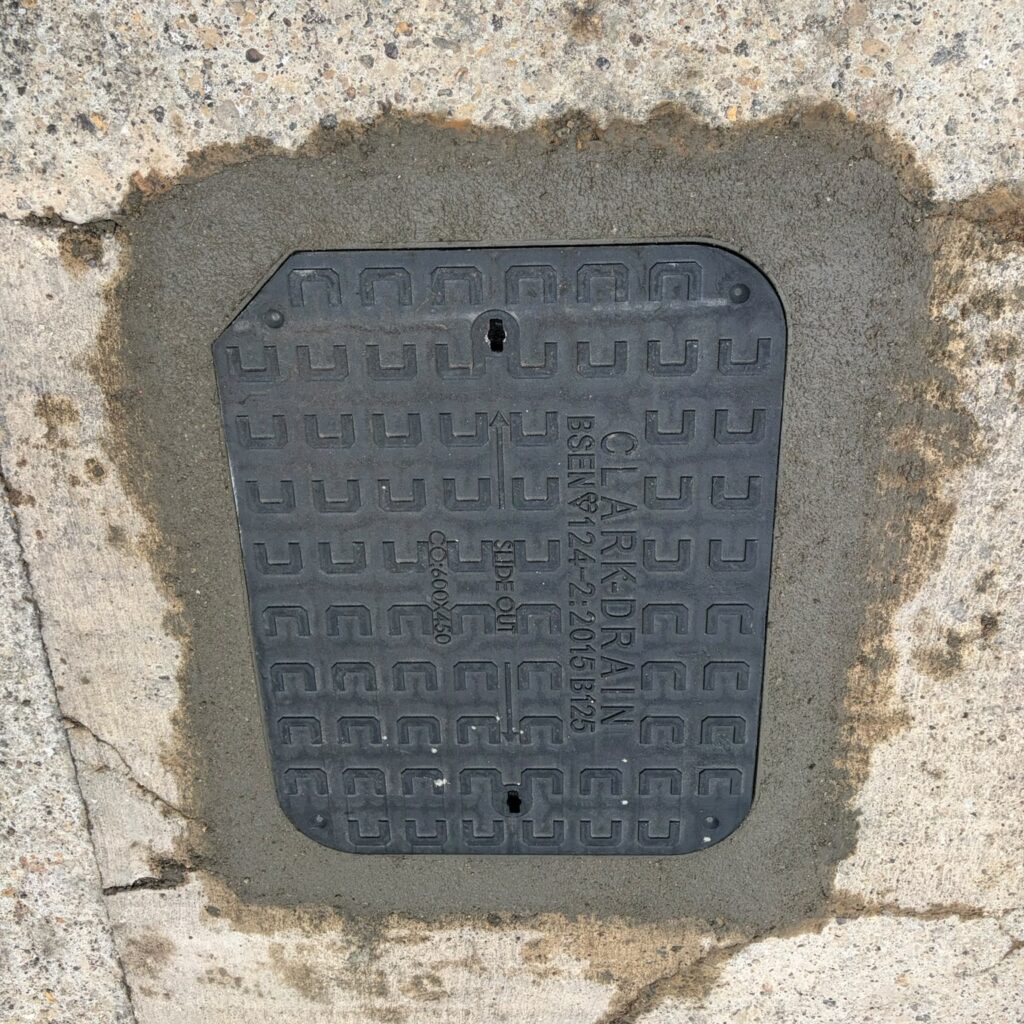 Inspection chamber cover set into its surrounding surface.
