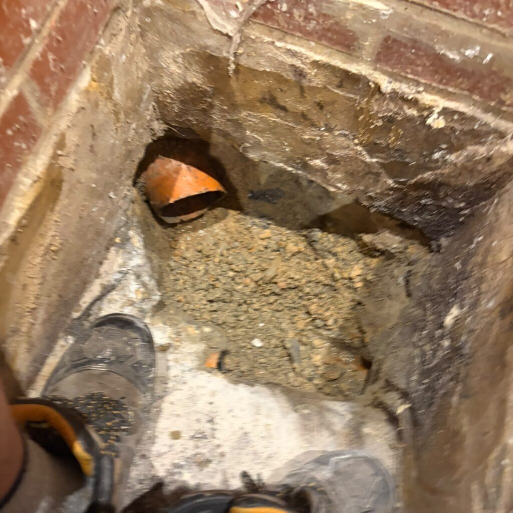 Exposed underground drainage pipe connections beside a property